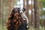 Woman carries Miniature American Shepherd