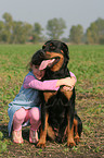 girl is snuggling a Rottweiler