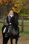 woman rides Frisian horse